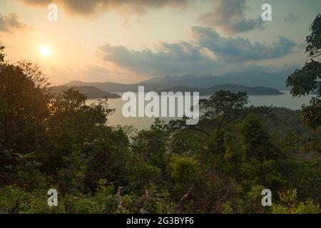 Tramonto dietro le nuvole, sulle isole tropicali Phrao NOK e Phrao Nai, visto dall'isola di Koh Chang, nel Golfo della Thailandia Foto Stock