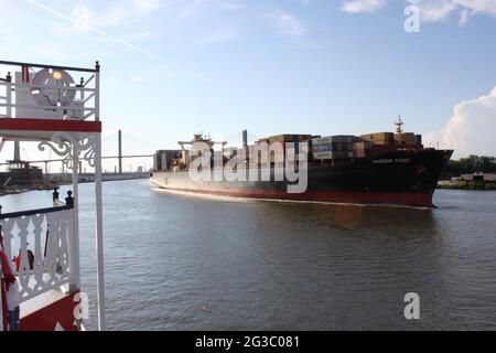 Massiccia nave container che passa attraverso un piroscafo turistico a pale sul fiume Savannah Georgia USA nel tardo pomeriggio. Foto Stock