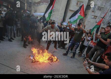 Gaza, territori palestinesi. 15 giugno 2021. I palestinesi bruciano la bandiera israeliana a Wehda Street, nel centro di Gaza, durante una manifestazione contro la controversa marcia della bandiera, organizzata da circa 5,000 nazionalisti israeliani di destra attraverso la città vecchia di Gerusalemme. Credit: Mohammed Talatene/dpa/Alamy Live News Foto Stock