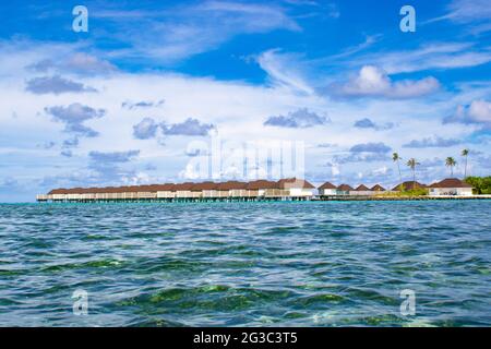 I bungallows sull'acqua all'Atollo Sud di Male, le Maldive dell'isola di Olhuveli all'Oceano Indiano, l'isola con le spiagge fiancheggiate da palme e un resort all-inclusive Foto Stock