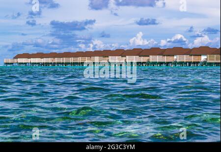 I bungallows sull'acqua all'Atollo Sud di Male, le Maldive dell'isola di Olhuveli all'Oceano Indiano, l'isola con le spiagge fiancheggiate da palme e un resort all-inclusive Foto Stock