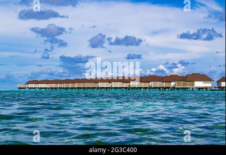 I bungallows sull'acqua all'Atollo Sud di Male, le Maldive dell'isola di Olhuveli all'Oceano Indiano, l'isola con le spiagge fiancheggiate da palme e un resort all-inclusive Foto Stock