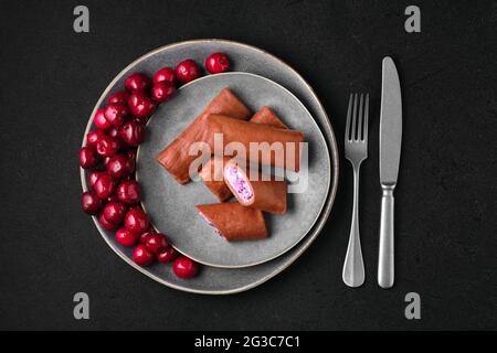 Vista dall'alto di sottili pancake al cioccolato ripieni di cagliata, mirtillo e ciliegia Foto Stock