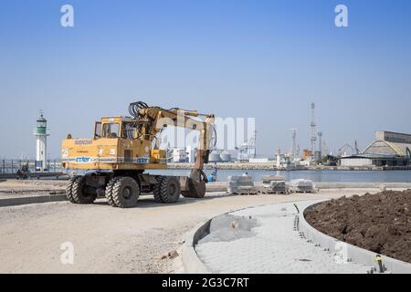 Lavori di costruzione e miglioramento della zona portuale - escavatore, piccolo faro, gru, silos e altri elementi dell'infrastruttura Foto Stock