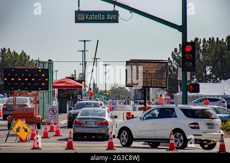 Gli automobilisti passano un cartello illuminato che li dirige verso un sito di vaccinazione del coronavirus ad Anaheim, California. Foto Stock