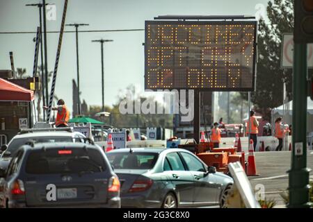 Gli automobilisti passano un cartello illuminato che li dirige verso un sito di vaccinazione del coronavirus ad Anaheim, California. Foto Stock