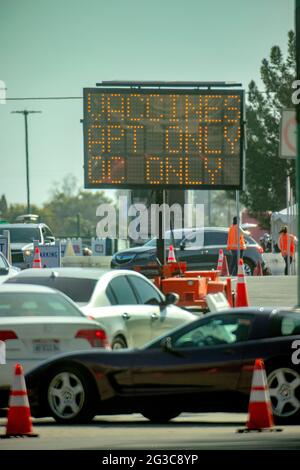 Gli automobilisti passano un cartello illuminato che li dirige verso un sito di vaccinazione del coronavirus ad Anaheim, California. Foto Stock