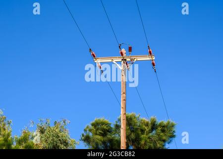 Linee elettriche su un palo di legno, su uno sfondo blu del cielo. Isola di Paros, Grecia Foto Stock