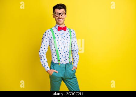 Ritratto di attraente ragazzo allegro che indossa una camicia di stampa che tiene le mani in tasche isolate su sfondo di colore giallo brillante Foto Stock