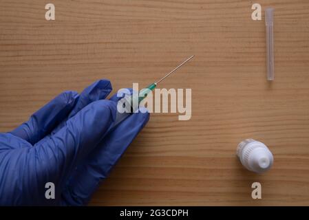 una mano guanto che tiene una siringa Foto Stock