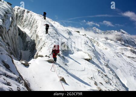 gruppo di scalatori in corda sul ghiacciaio - giornata di sole in montagna Foto Stock