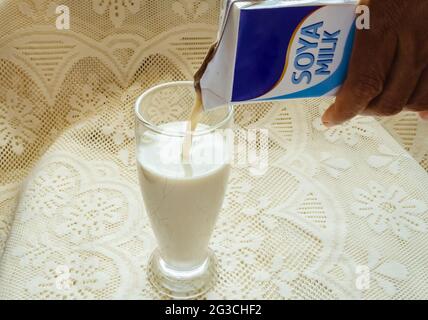 Versare il latte di soia in un bicchiere da bere Foto Stock