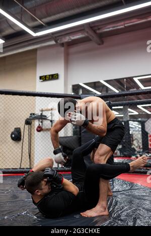 due lottatori uomini di grapping fanno la sottomissione wrestling. Pratica tecniche di combattimento, lotta sul pavimento in palestra, allenamento insieme, allenamento Foto Stock