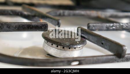 Stufa a gas sporca in cucina per cucinare con macchie di olio vegetale e detriti di cibo bruciato sulla superficie, primo piano. Messa a fuoco selettiva. G ricoperti di grasso Foto Stock