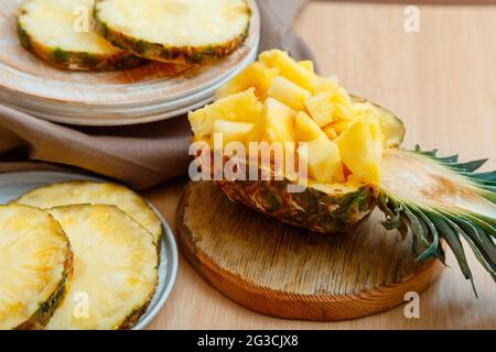 Insalata di ananas tritata in mezzo ananas. Fresco delizioso ananas tagliato a pezzi. Gustoso dessert estivo con frutta a fette di ananas e ingredienti Foto Stock