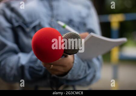 Giornalista In conferenza stampa, scrivere note, tenendo il microfono Foto Stock