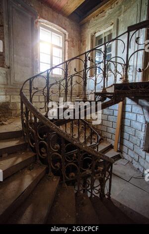 Vecchia scala a chiocciola d'epoca nel vecchio edificio abbandonato Foto Stock