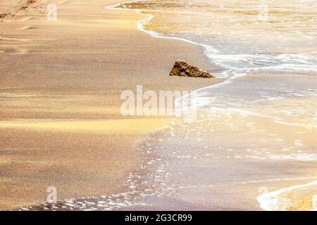 Sabbia colorata sulla spiaggia di Mirissa con onde oceaniche Foto Stock