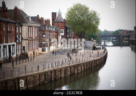 Una passeggiata di coppia lungo il fiume Ouse nel centro di York, nel nord dello Yorkshire. Un'area che è di solito occupato e brulicante di turisti e locali drinki Foto Stock
