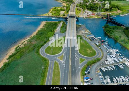 Vista aerea porto marittimo di vela piccolo con barche a motore allineate lungo il molo oceano vicino alla superstrada Foto Stock
