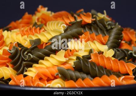 Tre colori Rotini Pasta. Pasta fusilli tricolore sfondo. Struttura astratta di pasta colorata. Modello di maccheroni. Cibo luminoso multicolore backdro Foto Stock