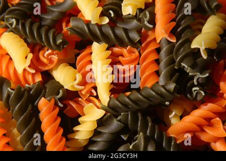 Tre colori Rotini Pasta. Pasta fusilli tricolore sfondo. Struttura astratta di pasta colorata. Modello di maccheroni. Cibo luminoso multicolore backdro Foto Stock