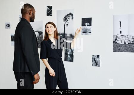 Ritratto di coppia elegante che indossa nero mentre si guardano le fotografie nella galleria d'arte moderna, copia spazio Foto Stock