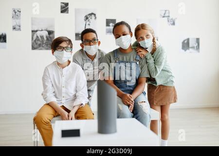 Vista frontale su diversi gruppi di bambini che indossano maschere mentre si guardano i dipinti nella galleria d'arte, spazio per le copie Foto Stock