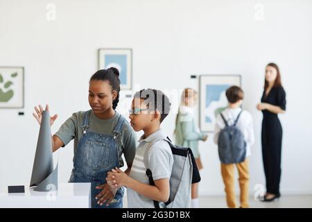 Ritratto minimo degli scolari che visitano la galleria d'arte e guardano le sculture moderne, spazio di copia Foto Stock