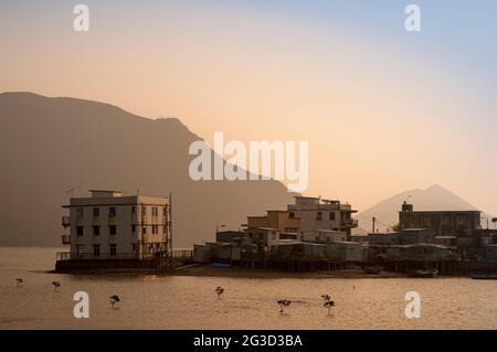 Il sole tramonta dietro lo strato di smog proveniente dalla Cina continentale sul Fiume delle Perle a Tai o, Isola di Lantau, Hong Kong Foto Stock