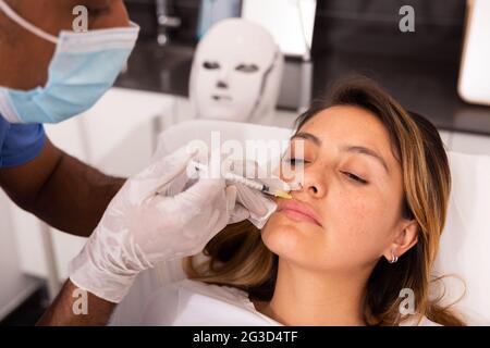 Cliente femminile durante la procedura di mesoterapia del viso in clinica di cosmetologia Foto Stock