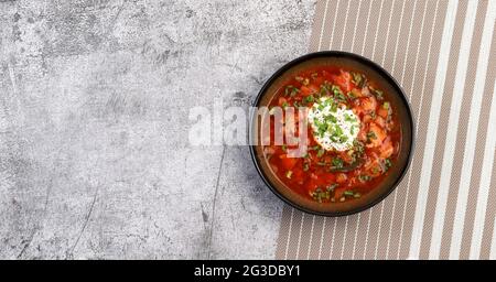 Borscht - zuppa di barbabietole con panna acida in una ciotola su fondo scuro. Vista dall'alto, disposizione piatta Foto Stock