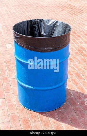 Barile in metallo con sacchetto in plastica per rifiuti sul pavimento della città Foto Stock