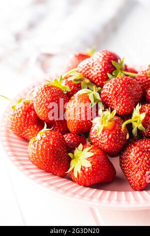 Fragole rosse mature intere su tavola bianca. Foto Stock