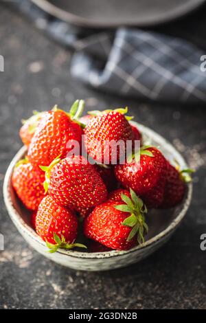 Fragole rosse mature intere in ciotola sul tavolo da cucina. Foto Stock