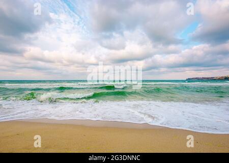 nuvoloso paesaggio marino in luce serale. onde schiacciare sulla spiaggia di sabbia. drammatico tempo natura sfondo Foto Stock