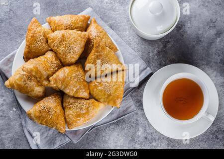 Piatto con deliziose samosas samsa con carne su sfondo grigio, vista dall'alto. Cibo uzbeko Foto Stock