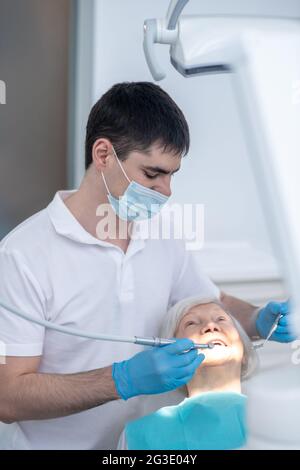 Dentista maschile che lavora con un paziente anziano con malattia periodentale Foto Stock