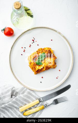 Cucina Italiana. Set di lasagne calde e gustose appena sfornate, su piatto, su fondo di pietra bianca, vista dall'alto, piatto Foto Stock