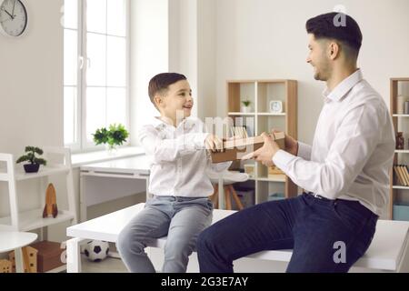 Il padre felice riceve un regalo di festa dal suo bambino amorevole. Momento di vacanza positivo. Foto Stock