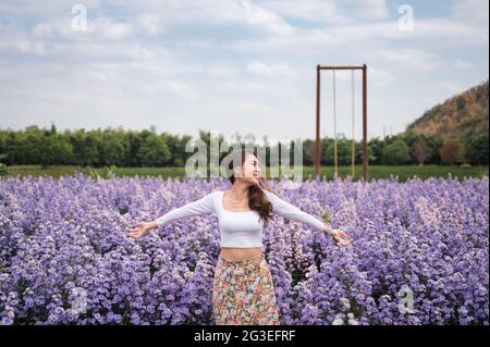 Bella giovane donna asiatica godendo sul fiore viola di margaret nel giardino Foto Stock