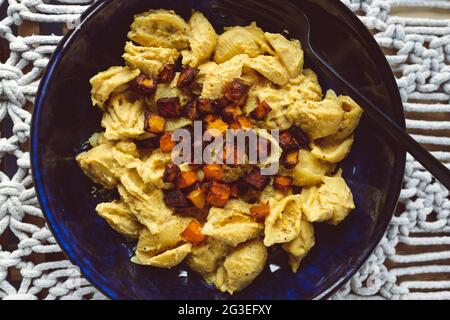 pasta di zucca cremosa vegana con cubetti di zucca tostati come condimento, sane ricette a base di piante Foto Stock