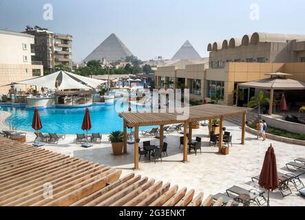Una vista da una piscina dell'hotel che guarda verso le Piramidi di Giza al Cairo in Egitto. Foto Stock