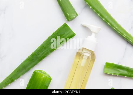 Colpo di bottiglia di aloe vera circondato da foglie verdi naturali di aloe vera Foto Stock