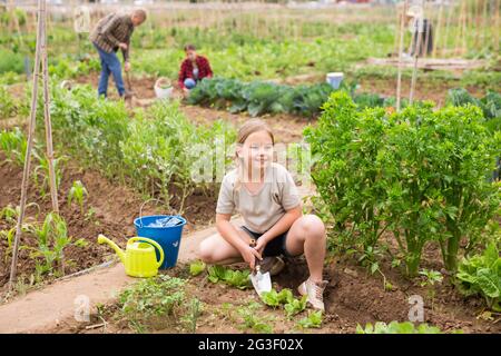 Bambina che aiuta i suoi genitori a lavorare in orto Foto Stock