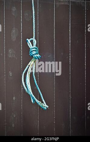 anello di corda in fibra sintetica blu sospeso su porta in legno verniciato scuro Foto Stock