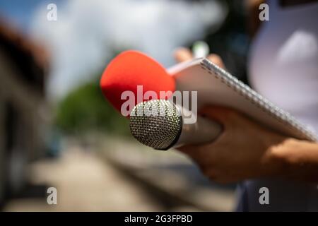 Giornalista In conferenza stampa, scrivere note, tenendo il microfono Foto Stock