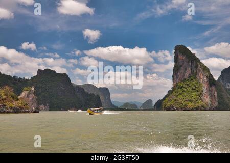 Spettacolari formazioni rocciose in mare con tipico taxi acqueo tailandese a Phang Nga Bay Thailandia Foto Stock