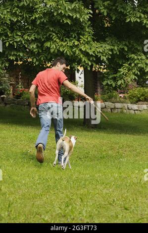 Uomo che gioca con il cane in giardino Foto Stock