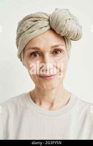 Minimo primo piano ritratto di bella donna matura che indossa foulard e sorridente alla fotocamera Foto Stock